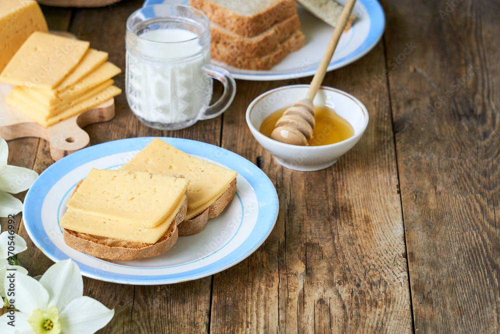Breakfast with cheese sandwich, milk and honey on a wooden table Breakfast with cheese sandwich, milk and honey on a wooden table