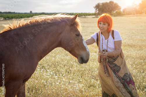 Woman with red hair near of a horse photo