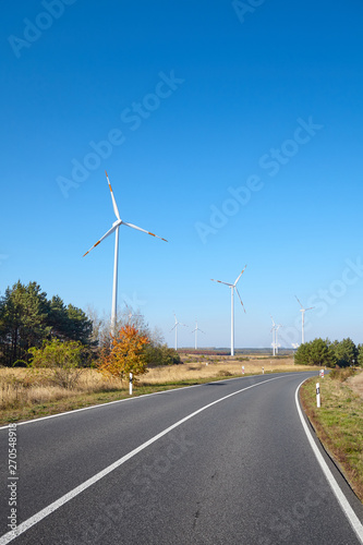 Picture of a road with with wind turbines in distance on a sunny day.