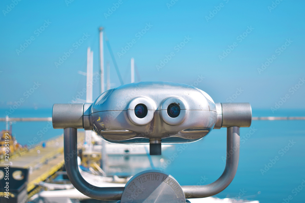 Binocular view of the yacht club and the skyline sea. Travel landscape with beautiful sky and sea. Looking through binoculars on the background of the sea