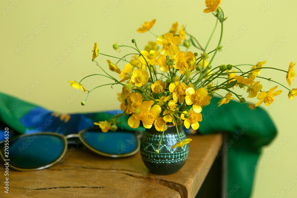 Wild yellow flowers, meadow buttercup, in small vase. Bouquet of fresh wild flowers, Ranunculus acris, indoor. 