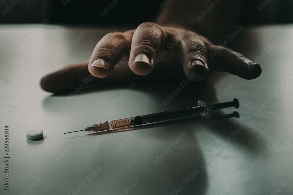Naklejka premium Addict at the table with a syringe heroin methamphetamine addiction