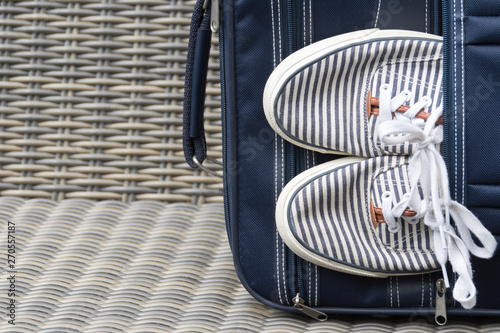 blue suitcase withe striped sneakers, against wicker background photo