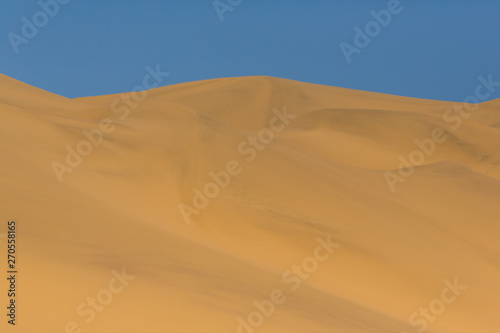 many sand dunes in Namib desert, blue sky