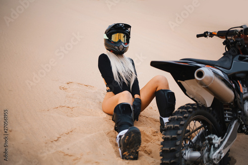 Fototapeta Naklejka Na Ścianę i Meble -  Woman with long white hair sitting near cross dirt motorcycle in desert