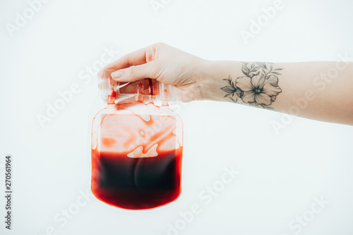 partial view of woman with tattoo holding blood bag isolated on white photo