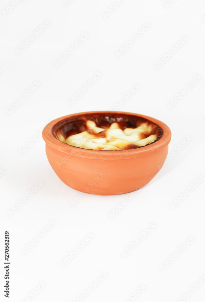 Turkish traditional sweet supangle dish in a clay plate on a white background Turkish traditional sweet supangle dish in a clay plate on a white background