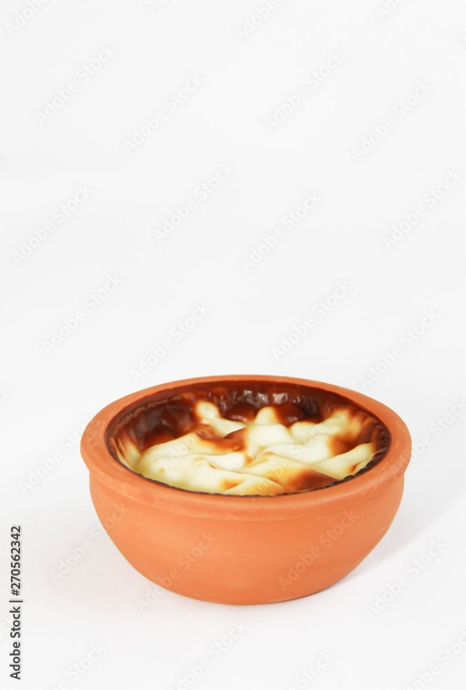 Turkish traditional sweet supangle dish in a clay plate on a white background Turkish traditional sweet supangle dish in a clay plate on a white background