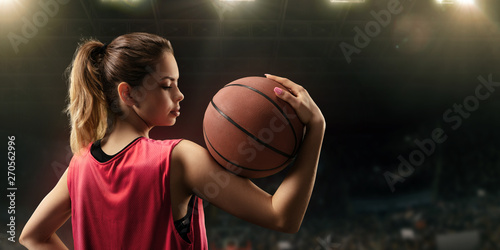 Female basketball player with ball on big professional arena 