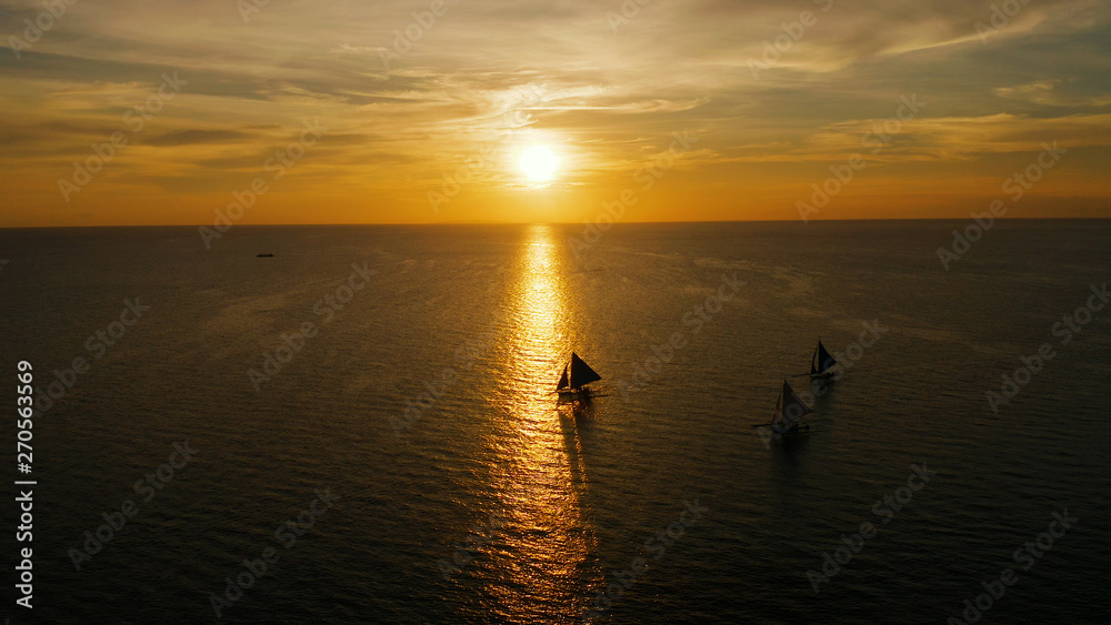 Sunset above the sea surface with sail boats, aerial view Boracay, Philippines. Reflected sun on a water surface. Sunset over ocean. Seascape, Summer and travel vacation concept