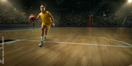 Female basketball player with ball on big professional arena 