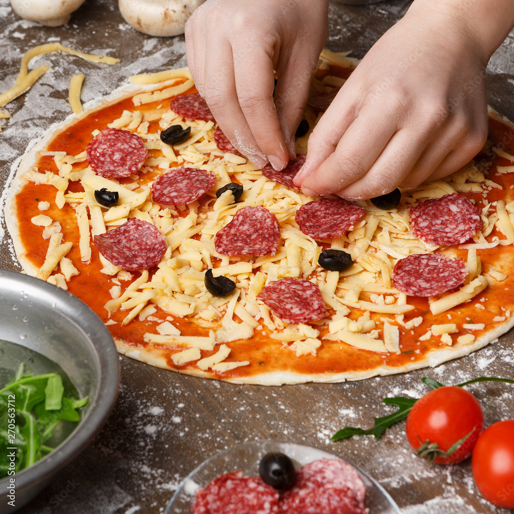 Woman Adding Salami To Pizza, Decorating With Various Ingredients