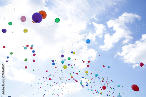  colored balloons fly in the blue sky with white clouds on the holiday. Bottom view. View from below.