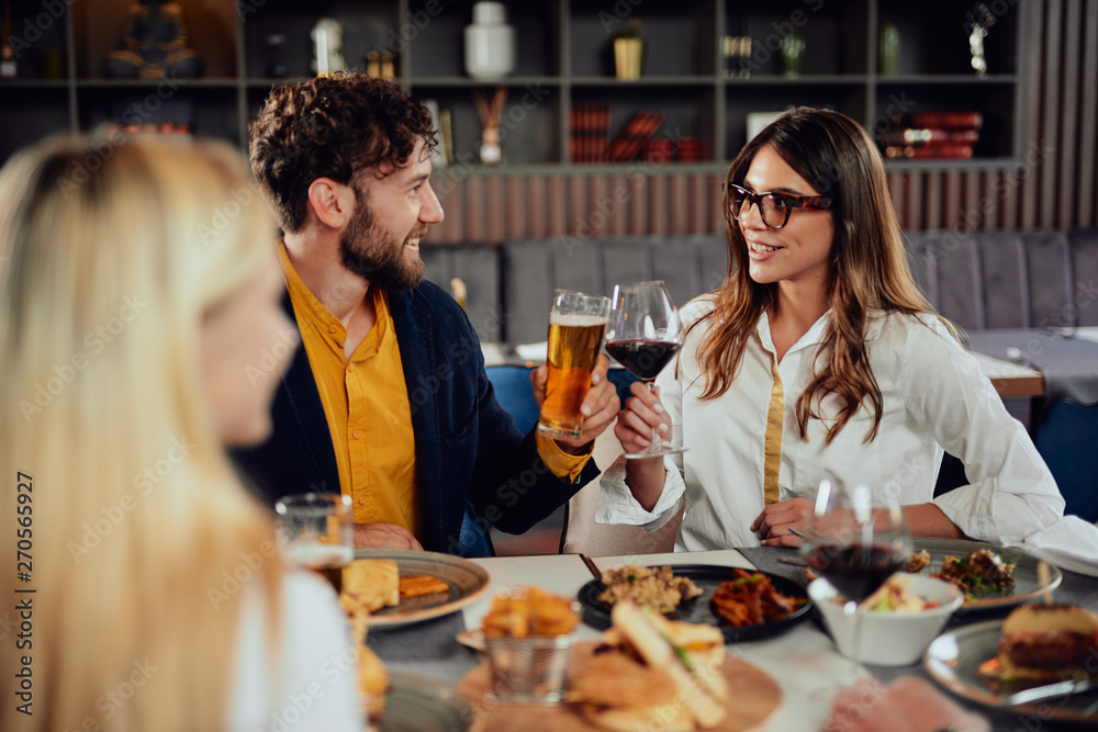 Cheerful Caucasian friends sitting in restaurant and making a toast. Cheerful Caucasian friends sitting in restaurant and making a toast.