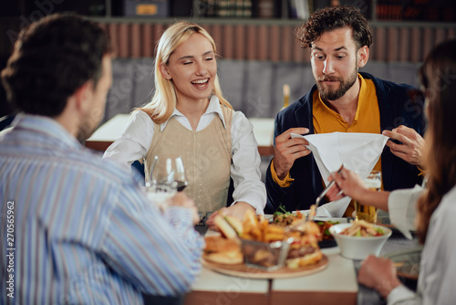 Multiethnic friends sitting at restaurant  drinking alcohol  chatting and having burgers for dinner.