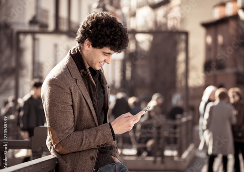 Young attractive happy hipster man talking on smart phone in european city