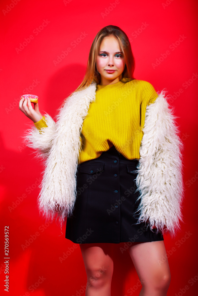 little cute blond teenage girl posing in fashion style with donut on red background, lifestyle people concept little cute blond teenage girl posing in fashion style with donut on red background, lifestyle people concept