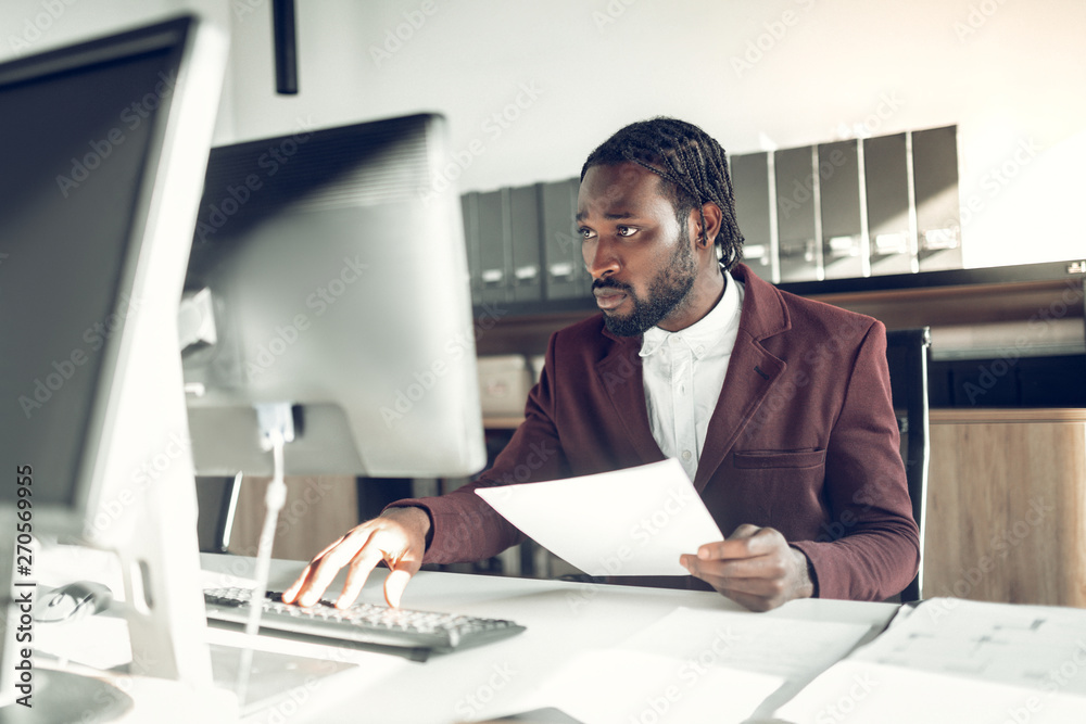 Naklejka premium Dark-skinned businessman working on computer in the office