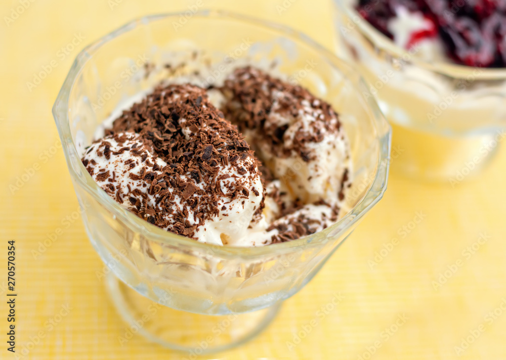 Ice cream dessert with chocolate and currant jam on yellow table-napkin. Selective focus Ice cream dessert with chocolate and currant jam on yellow table-napkin. Selective focus