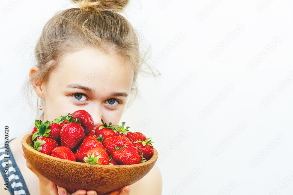 Wooden plate with strawberries in girl hand on light background, organic food concept Wooden plate with strawberries in girl hand on light background, organic food concept