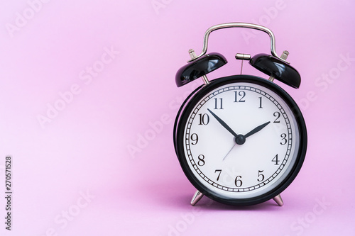 vintage black alarm clock on pink background