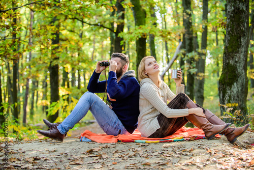 Man with binoculars and woman with metal mug enjoy nature park. Park date. Relaxing in park together. Happy loving couple relaxing in park together. Couple in love tourists relaxing picnic blanket