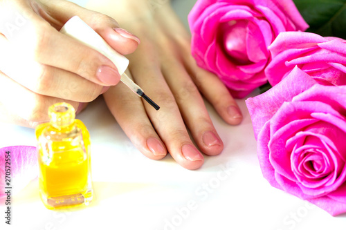 Beautiful manicured woman s nails with pink polish and oil for cuticles isolated. Nails care. Manicure  pedicure beauty salon. Beautiful rose red blossoms.