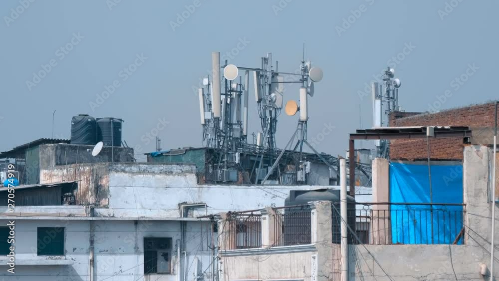 On the roof of the house in Delhi, India there are satellite dishes, mobile communication antennas, a radio relay dishes, blocks of the radio module of the base station equipment. Shot in motion On the roof of the house in Delhi, India there are satellite dishes, mobile communication antennas, a radio relay dishes, blocks of the radio module of the base station equipment. Shot in motion
