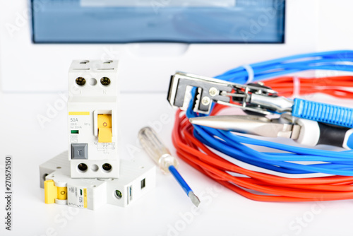 Automatic circuit breakers, distribution box, cable and digital multimeter on a white background. Electrical equipment. Accessories for electrical protection and control