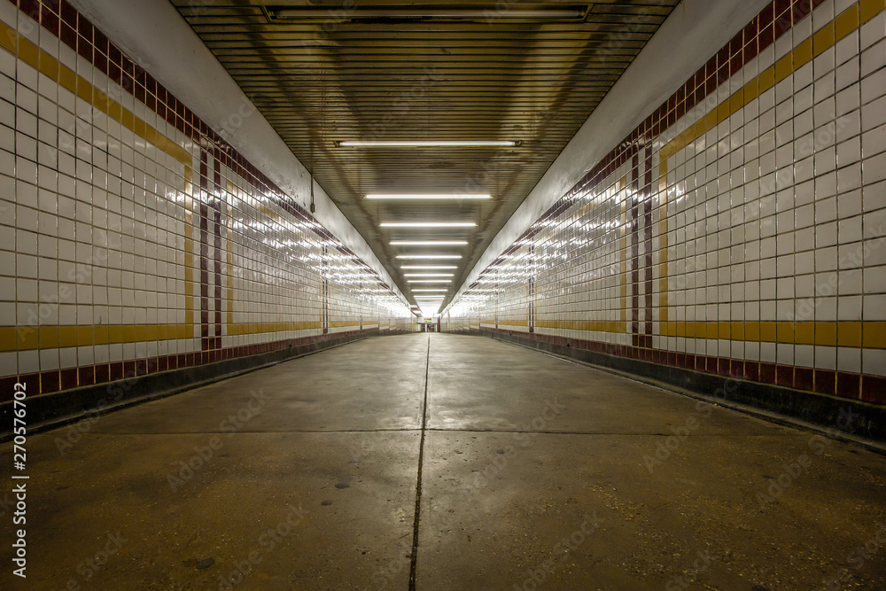 Long connecting hallway with colorful tiles in an underground subway station