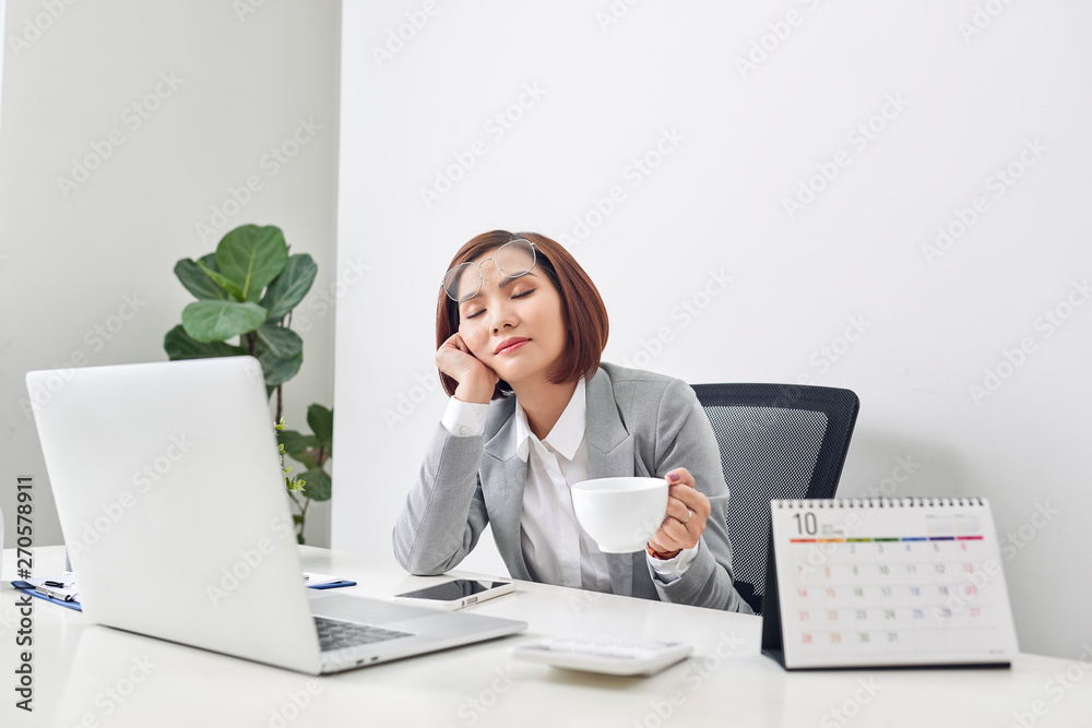 Tired young businesswoman taking a moment to relax at her desk with her eyes closed and head resting on her hand Tired young businesswoman taking a moment to relax at her desk with her eyes closed and head resting on her hand