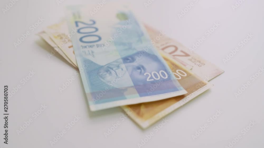 Hand slides Israeli shekel money on table and then takes it back Hand slides Israeli shekel money on table and then takes it back
