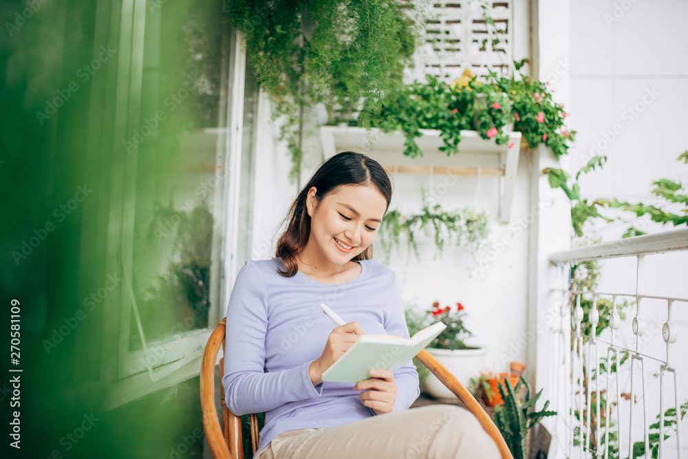 woman writing in notepad placed on white modern chair, freelancer at home woman writing in notepad placed on white modern chair, freelancer at home