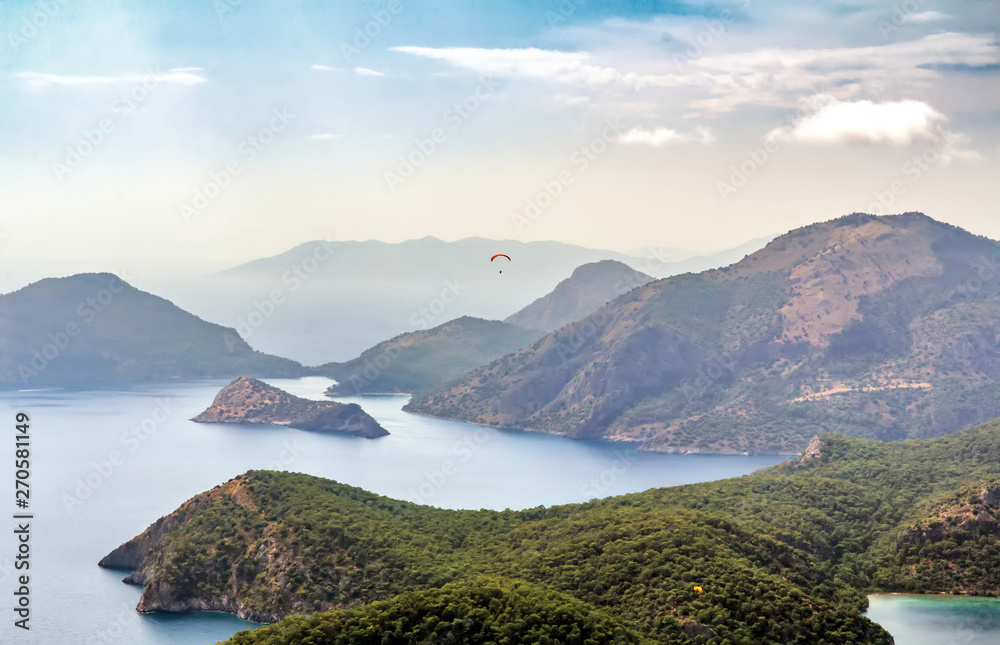 Oludeniz landscape with a floating paraglider in the sky, view from the mountain at sunset.