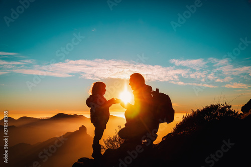 father and little daughter travel in mountains at sunset