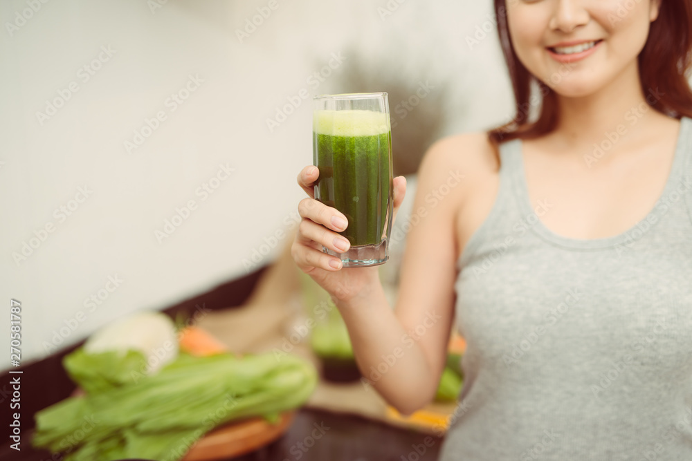 Pretty young woman drinking a vegetable smoothie in her kitchen Pretty young woman drinking a vegetable smoothie in her kitchen