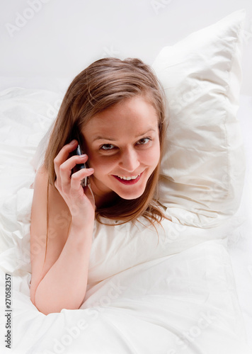 Woman in bed talking on phone.