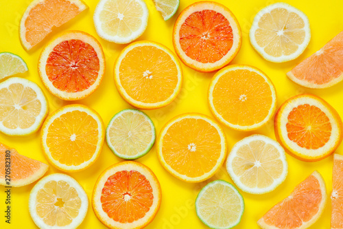 Citrus slices pattern on yellow background from above. Top view of orange, grapefruit, lime and lemon fruit slices on yellow background. Fruit summer cocktail pattern design