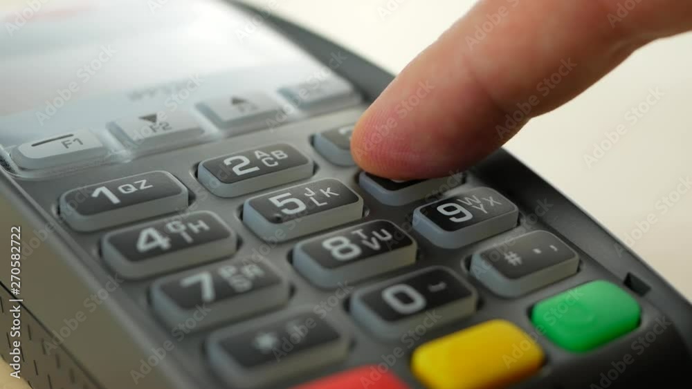 Customer paying with contactless credit card with NFC technology. Credit card reader machine at bar counter. Finger entering PIN code Customer paying with contactless credit card with NFC technology. Credit card reader machine at bar counter. Finger entering PIN code