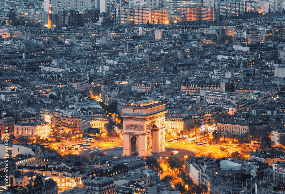 Aerial view of the Arc de Triomphe de l'Etoile (The Triumphal Arch) in Paris at sunset with traffic lights.