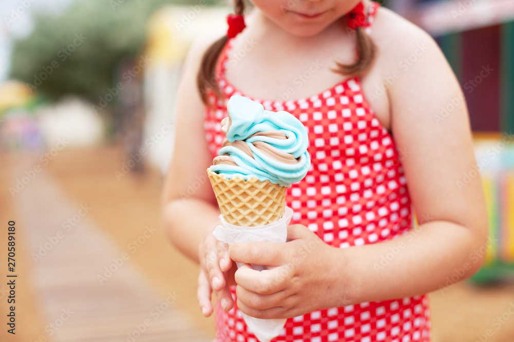 young girl in red bathing suit eating blue ice cream in horn on the beach young girl in red bathing suit eating blue ice cream in horn on the beach