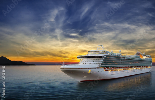 Luxury cruise ship sailing to port on sunset. 