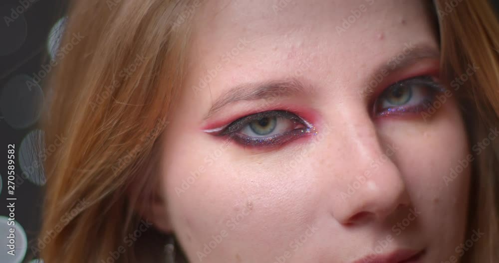 Portrait of blonde model with bright make-up watching downwards flirting with camera on bokeh background. Portrait of blonde model with bright make-up watching downwards flirting with camera on bokeh background.