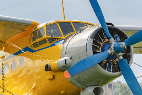 Yellow pilots cabin and engine with blue four blade propeller of soviet aircraft biplane Antonov AN-2 closeup