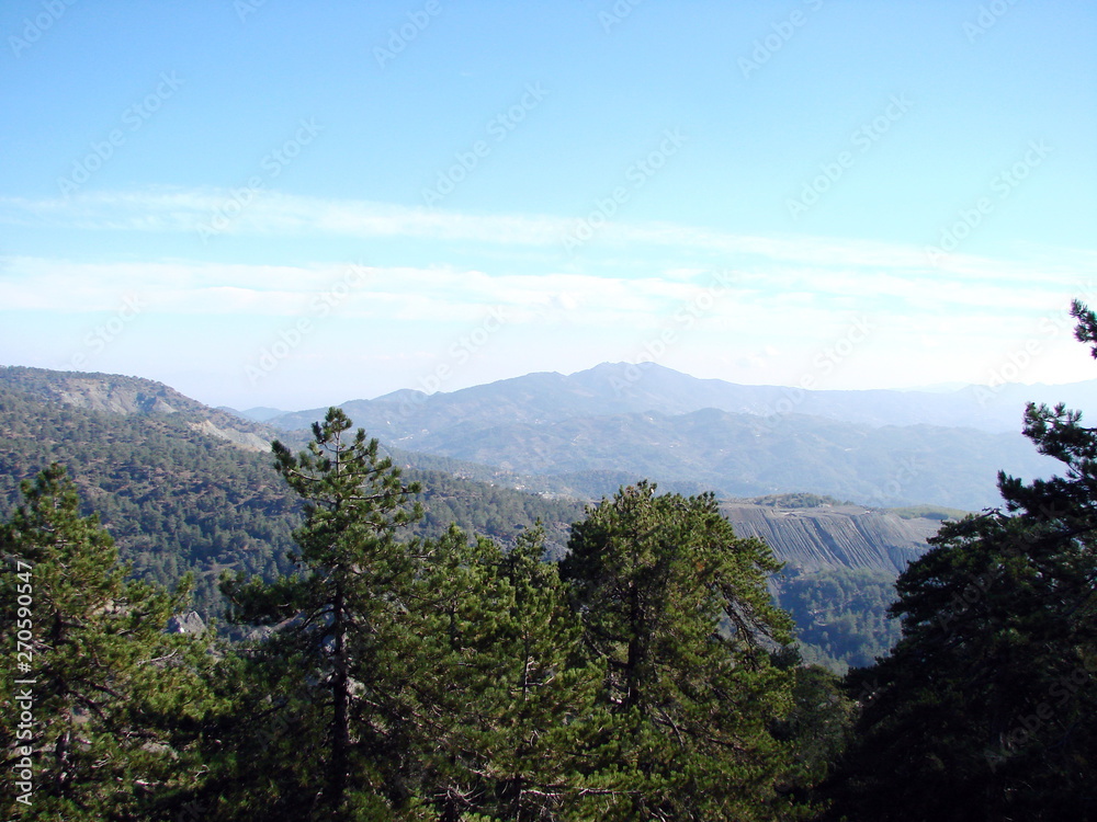 Panorama from the top of a mountain is a barely cloudy blue sky that stretches to the horizon over the boundless mountain ranges.