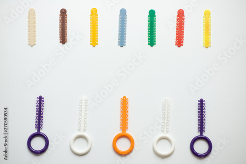 a multi-colored orthodontic ligatures for alignment of the orthodontist s teeth on a light background