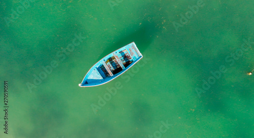 Beautiful turquoise ocean water with wooden boat on the water. Top view aerial photo