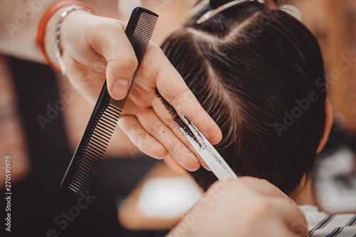 Close-up master hairdresser does hairstyle with scissors and comb. Concept Barbershop
