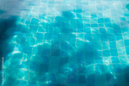 Abstract blue water with shiny rays. Clear water with shining caustics. Water reflection background in swimming pool.