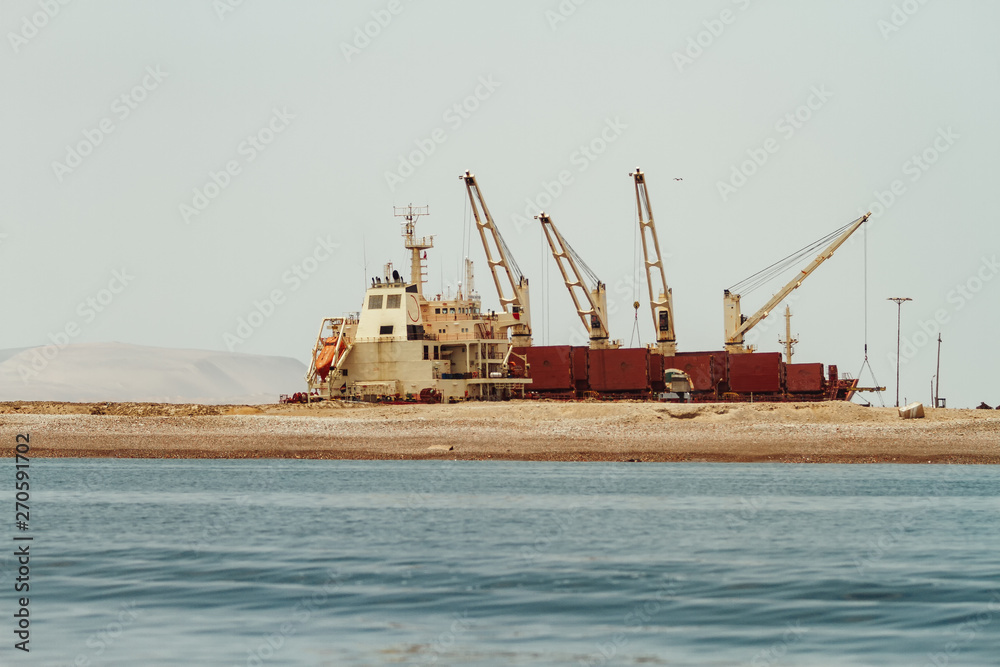 Cranes with boat and containers on the coasts of Paracas, Peru